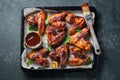 Roasted chicken wings in barbecue sauce with sesame seeds and parsley in a baking tray on a dark table. Top view. Tasty snack for Royalty Free Stock Photo