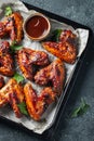 Roasted chicken wings in barbecue sauce with sesame seeds and parsley in a baking tray on a dark table. Top view. Tasty snack for Royalty Free Stock Photo