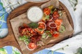 Roasted chicken wings with paprika, white sauce and vegetables on wooden board on the table