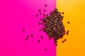 Aromatic Roasted coffee beans pile pink and yellow background. top view