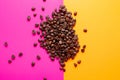 Aromatic Roasted coffee beans pile pink and yellow background. top view