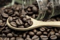 Roasted coffee beans in wooden spoon and spread on black table with white coffee cup Royalty Free Stock Photo