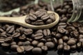 Roasted coffee beans in wooden spoon and spread on black table with white coffee cup Royalty Free Stock Photo