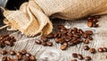 Roasted coffee beans on a brown wooden background with coarse roughly woven burlap, grunge texture. Place for your text Royalty Free Stock Photo