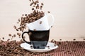 Roasted coffee beans falling down into white cup standing on a b Royalty Free Stock Photo