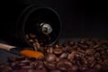 roasted coffee beans flow down from manual coffee grinder with orange brush, soft focus