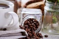 Roasted coffee beans get out of overturned glass jar on homespun tablecloth, selective focus, side view