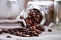 Roasted coffee beans get out of overturned glass jar on white background, selective focus, side view