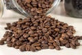 Roasted coffee beans get out of an overturned and open glass jar Royalty Free Stock Photo