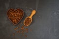 Roasted coffee beans in heart shaped bowl on black stone table. Royalty Free Stock Photo