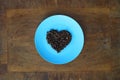 Roasted coffee beans in heart shaped bowl on dark background. Royalty Free Stock Photo