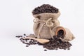 Roasted coffee beans in hemp sacks and wooden spoon on white background.