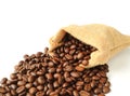 Roasted coffee beans scattered from burlap bag on white background Royalty Free Stock Photo