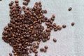Roasted coffee beans scattered on a grey textile background, top view, left side, free space
