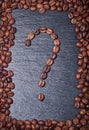 Roasted coffee beans in the shape of a question mark on a black background