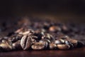 Roasted coffee beans spilled freely on a wooden table.