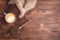 Roasted coffee beans waking up from a jute coffee bag on an wooden table. Close-up. Cup of coffee. Royalty Free Stock Photo