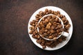 Roasted coffee beans in white cup at dark table. Royalty Free Stock Photo