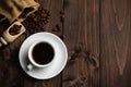 Roasted coffee beans with a white cup of espresso on a dark wooden table, rustic, top view Royalty Free Stock Photo