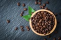 Roasted coffee beans on wooden bowl green leaf and dark background - top view Royalty Free Stock Photo