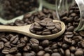 Roasted coffee beans in wooden spoon and spread on black table with bottle glass Royalty Free Stock Photo