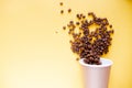 Roasted coffee grains and takeaway cup top view. Craft paper tea cup on orange background flat lay. Cafe web banner with copyspace Royalty Free Stock Photo