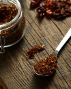 Roasted dry chili pepper powder in jar and in the spoon. Dried chilli on background. Wood board background. Royalty Free Stock Photo