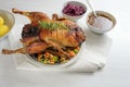 Roasted duck with apple, plum filling, served with vegetables, red cabbage, potatoes and sauce, festive Christmas meal on a white