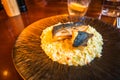 Roasted fish fillet on risotto on decorative plate, drink, glass on restaurant table