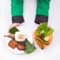 Roasted fish with fried tempeh, petai, cucumber, lettuce, leunca, fried shallot, and white rice with hand Royalty Free Stock Photo