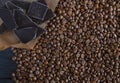 Roasted fragrant beans of black coffee are scattered on a black wooden table, on which black chocolate is lying Royalty Free Stock Photo