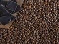 Roasted fragrant beans of black coffee are scattered on a black wooden table, on which black chocolate is lying Royalty Free Stock Photo