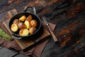 Roasted Garlic Potatoes , in frying cast iron pan, on old dark  wooden table background, with copy space for text Royalty Free Stock Photo