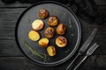 Roasted Garlic Potatoes, on plate, on black wooden table background, top view flat lay Royalty Free Stock Photo