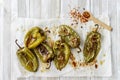 Roasted green peppers with spices on wooden board