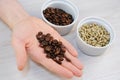 Roasted and green unroasted coffee in bowls. Freshly roasted coffee beans on the palm closeup Royalty Free Stock Photo