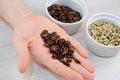 Roasted and green unroasted coffee in bowls. Freshly roasted coffee beans on the palm closeup Royalty Free Stock Photo