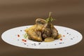 Roasted guinea fowl with potatoes, with green herbs, placed on a white plate