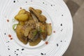 Roasted guinea fowl with potatoes, with green herbs, placed on a white plate