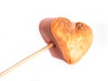 Roasted heart form marshmallows on a skewer in female hand on white background Royalty Free Stock Photo