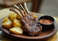 Roasted lamb rack meat with baked potatoes and gravy sauce on plate on restaurant table.Macro.AI Generative