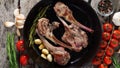 Roasted lamb ribs with rosemary, tomatoes, garlic on pan on dark rustic wooden background, top view, long width banner