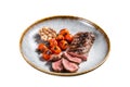 Roasted Lamb tenderloin meat in plate with grilled tomato and garlic, mutton sirloin fillet steak. Isolated on white Royalty Free Stock Photo