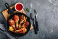 Roasted Lemon Chicken Legs with chili sauce and sesame in cast iron pan on dark stone background