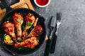 Roasted Lemon Chicken Legs with chili sauce and sesame in cast iron pan on dark stone background