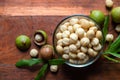 Roasted macadamia nut in glass bowl on wooden table background