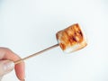 Roasted marshmallows on a skewer in female hand on white background Royalty Free Stock Photo