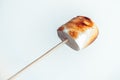 Roasted marshmallows on a skewer on white background