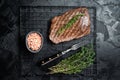 Roasted medium rare flank beef steak with thyme. Black background. Top view