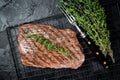 Roasted medium rare flank beef steak with thyme. Black background. Top view